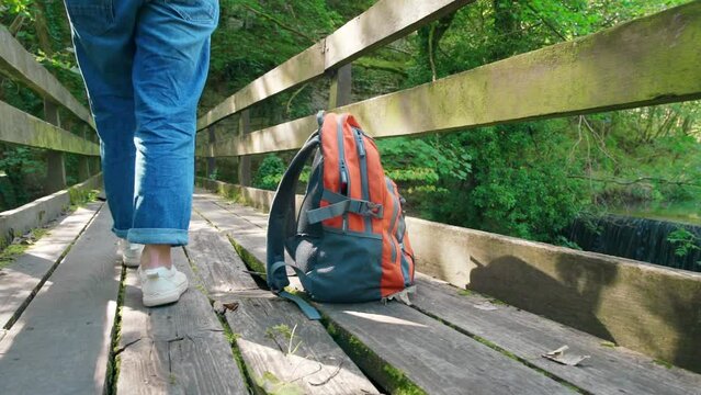 Orange backpack  on old bridge against waterfall . Travel concept.
