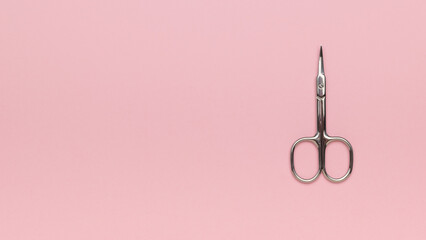 Metal nail scissors on a pink background.