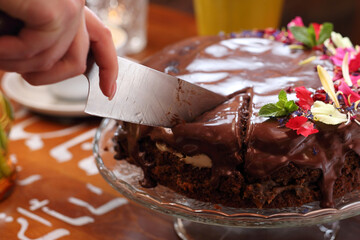 Cutting a chocolate cake with chocolate glaze, selective focus, close-up, with blurred background