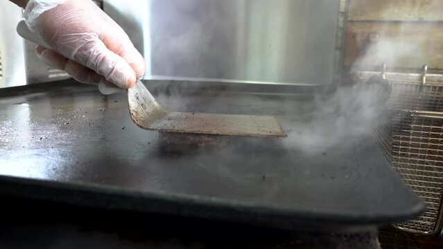 A hamburger patty grilling on a flat top grill