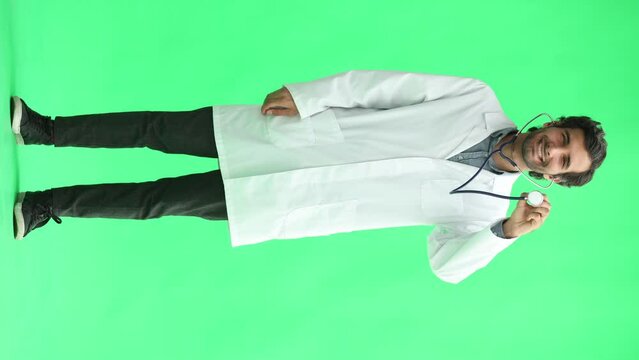 male doctor in a white coat on a green background demonstrates a statoscope