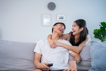 Happy relaxed young family couple homeowners or renters lying on big cozy sofa, enjoying carefree leisure weekend time, celebrating moving into new contemporary apartment, tenancy concept.