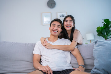 Happy relaxed young family couple homeowners or renters lying on big cozy sofa, enjoying carefree...