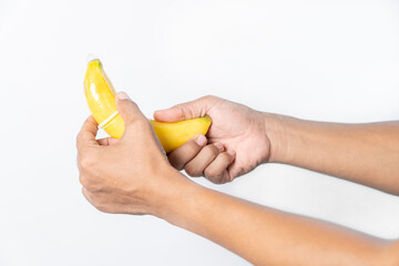 Hand shows how to put a condom on the penis using a banana as a demonstration.