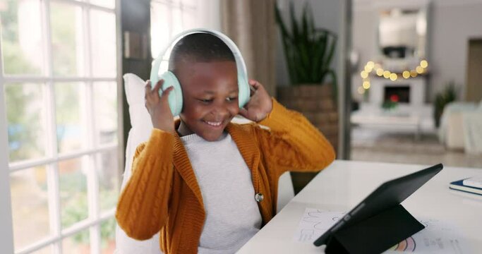 Headphones, tablet and boy child dancing to music, playlist or album online in the dining room. Digital technology, young and African kid moving while listening to a song or radio at modern home.