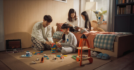 Successful Korean Parents Playing with Kids in Children's Room. Mother and Daughter Reading Fairy Tales, Father and Son Using Building Blocks for Constructing a Tower