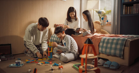 Happy Korean Family Playing Together in Children's Room. Mother and Daughter Reading Fairy Tale...