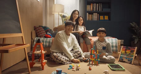Fotobehang Happy Korean Family Portrait with Adults And Kids Looking at Camera and Smiling in Children's Room. Mother and Daughter Reading Fairy Tale Stories, Father and Son Play with Construction Blocks. © Kitreel
