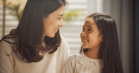 Portrait of a Happy Korean Mother and Cute Daughter at Home, Smiling and Looking at Eachother. Beautiful Moment of Affection Shared Btween a Little Girl and her Mom
