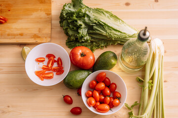 Fresh vegetables in white plates and on a wooden table.