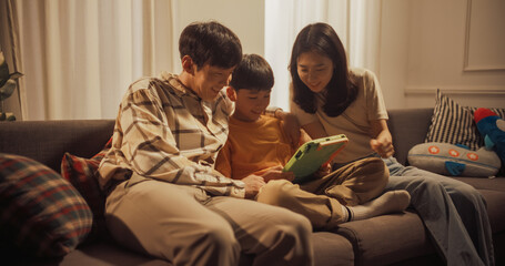 Portrait of Happy Korean Family Using Digital Tablet Computer While Sitting in the Living Room....