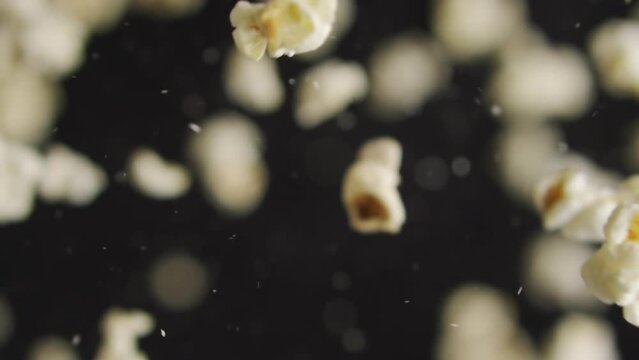 Appetizing popcorn flies in slow motion on a black background. Fast food for movies in cinema