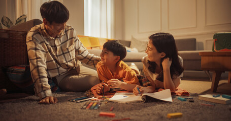 Happy Korean Family At Home: Cute Little Boy Drawing In Notebook On The Floor And Showing His...