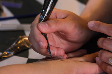 Close-up of a henna tattoo drawing process on the hand.