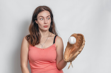 Woman in a pink T-shirt catches a ball with a baseball glove. Surprised facial expression.