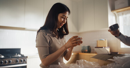 Portrait of Cute Korean Couple Unpacking Their Kitchen Dishes After Moving in to Their New Bright...
