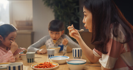 Happy Korean Family Members Enjoying Delicious Food Together. Young Parents and Their Two Children Eating Traditional Dishes at Home While Sitting at Their Kitchen Table