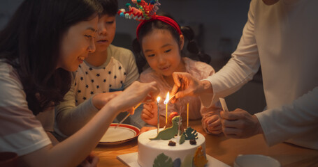 Family Memories: Portrait of Cute Little Girl Making a Wish Before Blowing Out her Birthday Cake Candles. Young Korean Couple Celebrating Their Daughter Growing Up, Clapping and Cheering