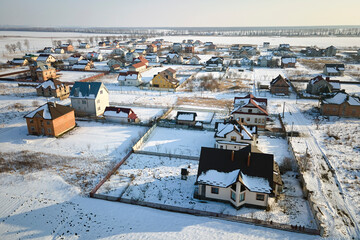 Aerial view of residential houses with snow covered roofops in suburban rural town area in winter