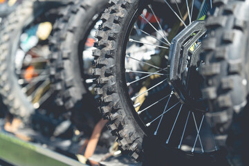 Motocross motorcycle wheels Components of an enduro motorcycle Tires for mud. Part of a dirt bike on a dirt road in a cornfield with warm light. Copy space. - obrazy, fototapety, plakaty