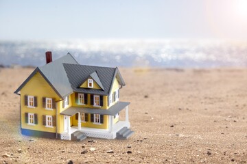 Model of house on sandy beach background