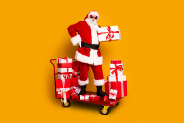Full size photo of eccentric santa pile stack christmas giftbox pushcart trolley isolated on yellow...