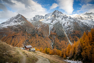 Alpine valley in autumn in Val d'Hérens in Switzerland with mountains, larch trees and small chalets - 677731107