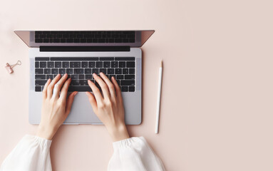 Top view of white collar woman hands typing, using keyboard of a laptop computer for online shopping, learning, design, email on a paste pink background desk at office. Copy space for text, advertisin