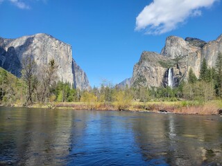 Beautiful view of lake and green trees in a forest with waterfall on a rock