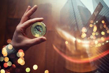 Double exposure businessman with vintage compass in a hand and skyscraper.  concept to make...