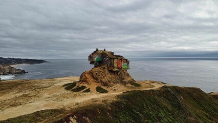 Old wooden house on the edge of a rock at Gray Whale Cove State Beach in California