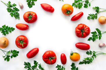 Red and yellow tomatoes, fresh tomatoes of various colors and cultivar, parsley, onion, garlic on a white background with space for text. Top view, flat lay