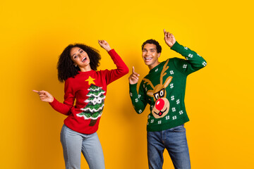 Photo of excited carefree guy girl dressed christmas ugly print pullovers dancing having fun isolated yellow color background