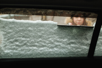 View from inside of woman clean car from snow