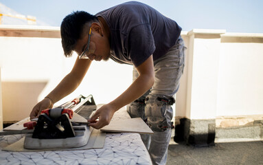 latin worker cutting floor tiles to tile the floor of home