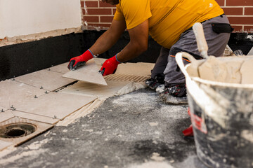 Tiler placing the ceramic tile on the floor. Grouting ceramic tiles. renewal. Construction. Tiler's...