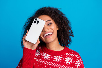 Photo of cheerful joyful girl wear trendy ornament sweater hand hold show modern apple iphone device isolated on blue color background