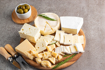 Wooden board with various cheese and olives. Brie. Camembert. Parmesan, feta, blue cheese. Italian, French cheese.