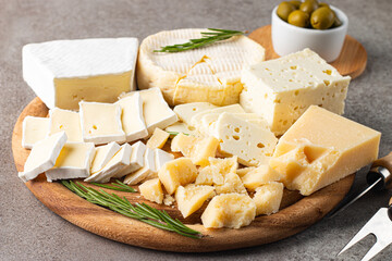 Wooden board with various cheese and olives. Brie. Camembert. Parmesan, feta, blue cheese. Italian, French cheese.