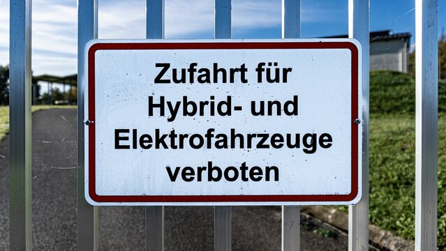 Access is prohibited for hybrid and electric vehicles sign on a fence. Translated from german.