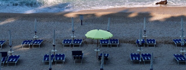 Spiaggia parzialmente in ombra con sdraio ed ombrelloni