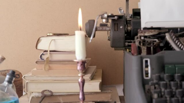 candle burning in candlestick, stack old books, letters, vintage typewriter, creative process and literary creation concept, atmosphere journalism and reportage, articles about antiques and collecting