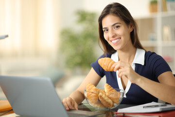 Happy student e-learning eating croissants