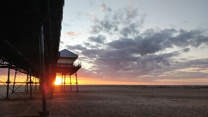 Beautiful sunset scene at a beach with a pier and a lifeguard tower