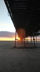 Vertical of a beautiful sunset at a sandy beach with a pier