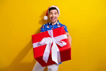Photo of cheerful very happy guy celebrate traditions atmosphere christmas party midnight take gift box isolated on yellow color background