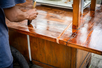 a carpenter varnishes a piece of wood with his hands