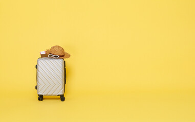 gray suitcase with sunglasses, hat and passport isolated on yellow copy space background....