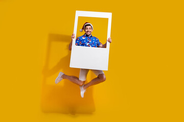 Full body photo of carefree crazy person jumping hold paper album card isolated on yellow color...