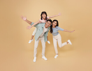 Full body portrait happy asian family standing giving piggyback ride to daughter, sit on back...